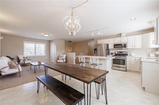 dining room featuring rail lighting, recessed lighting, baseboards, and a chandelier