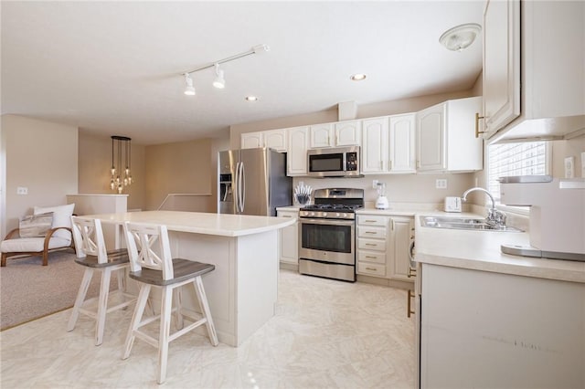 kitchen with a center island, a breakfast bar, appliances with stainless steel finishes, white cabinetry, and a sink