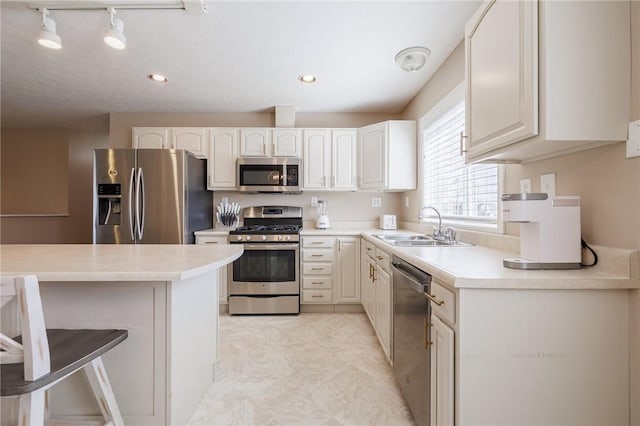 kitchen featuring a sink, stainless steel appliances, a breakfast bar, and light countertops