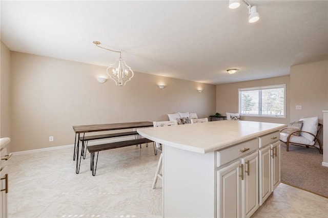 kitchen with a center island, an inviting chandelier, a breakfast bar area, light countertops, and hanging light fixtures