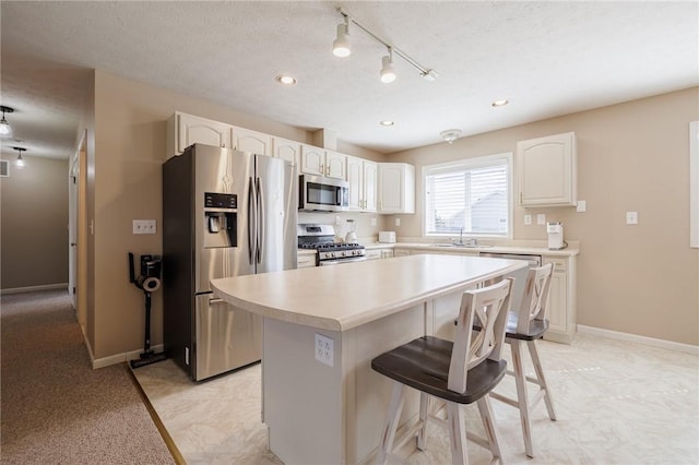 kitchen featuring a breakfast bar area, a kitchen island, white cabinets, appliances with stainless steel finishes, and a textured ceiling