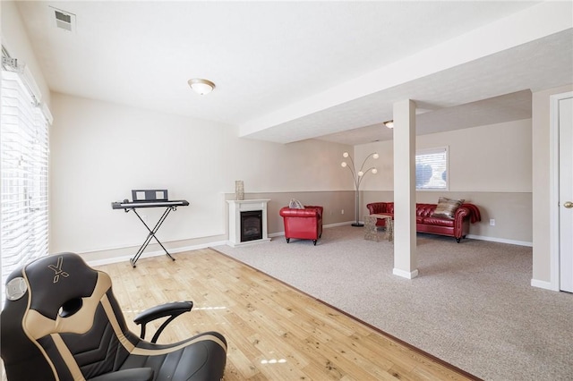 sitting room with wood finished floors, a fireplace, visible vents, and baseboards