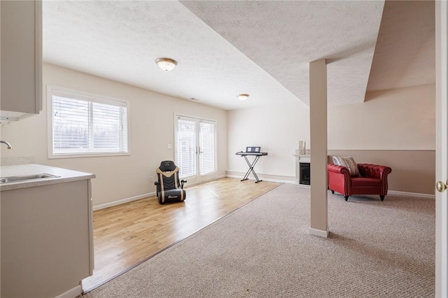 interior space with a fireplace, a textured ceiling, baseboards, and a sink