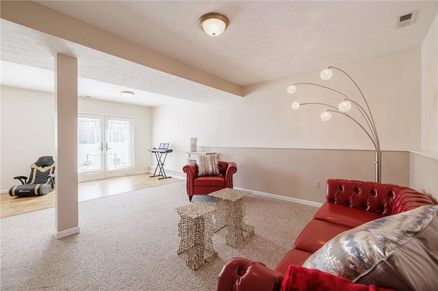 carpeted living area featuring visible vents, baseboards, and french doors