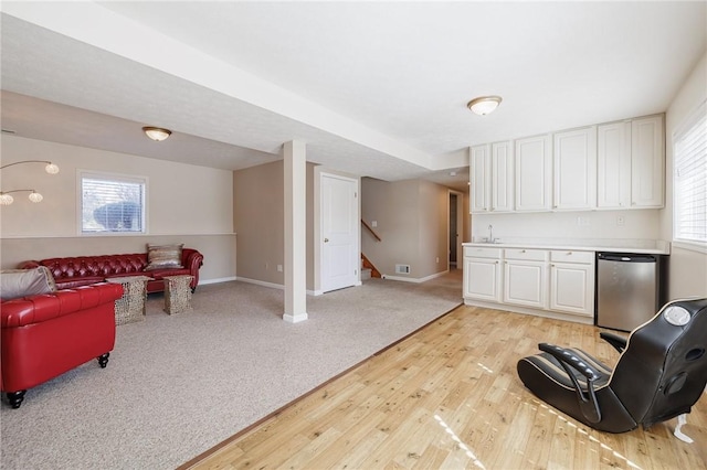 interior space featuring stairway, visible vents, baseboards, light wood finished floors, and light colored carpet