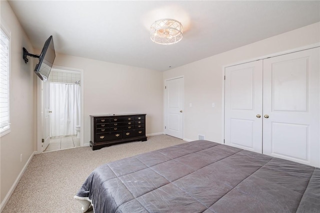 carpeted bedroom with a closet, baseboards, and ensuite bath