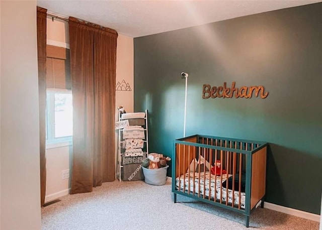 carpeted bedroom with a crib and baseboards