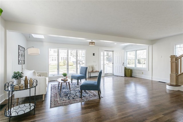 living room featuring stairs, dark wood-type flooring, and plenty of natural light