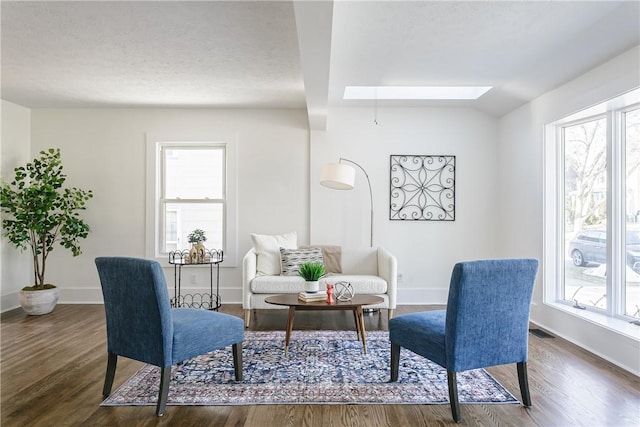 sitting room with a skylight, wood finished floors, and baseboards