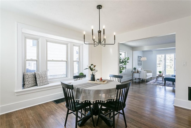 dining area with dark wood finished floors, a chandelier, and baseboards