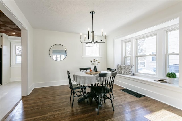 dining room with visible vents, dark wood-type flooring, a notable chandelier, a textured ceiling, and baseboards