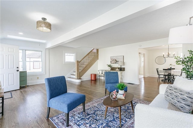 living area featuring wood finished floors, visible vents, baseboards, stairs, and a chandelier