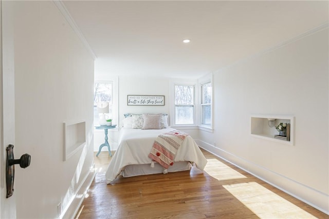 bedroom featuring recessed lighting, wood finished floors, baseboards, and ornamental molding