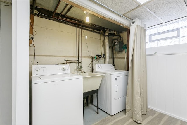 washroom with laundry area, light wood-style flooring, wooden walls, and separate washer and dryer