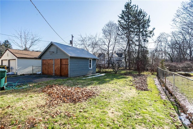 view of yard with a detached garage, an outdoor structure, and fence