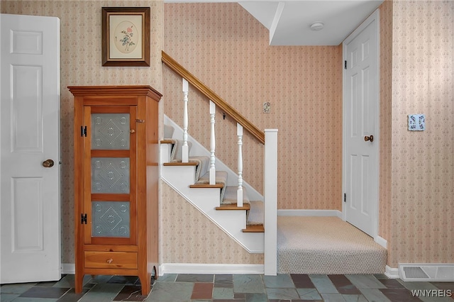 staircase with visible vents, baseboards, and wallpapered walls