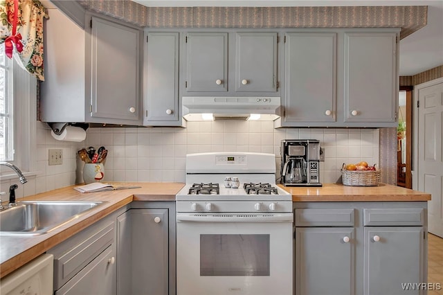 kitchen with white range with gas cooktop, under cabinet range hood, and gray cabinetry