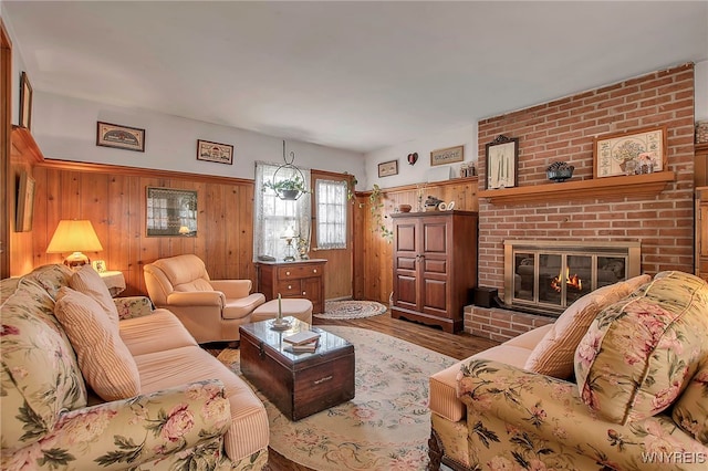 living room with wooden walls, a brick fireplace, and wood finished floors