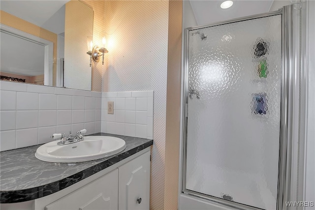 full bathroom with a shower stall, wallpapered walls, and vanity