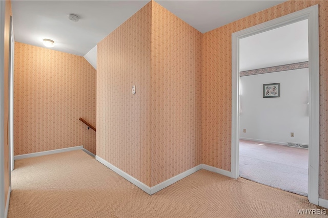 corridor with carpet, visible vents, wallpapered walls, lofted ceiling, and an upstairs landing