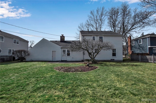 rear view of property with a lawn and fence