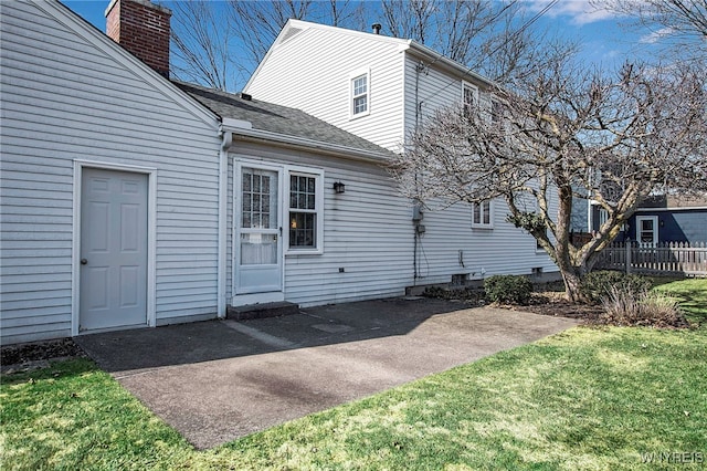 back of house featuring fence, roof with shingles, a chimney, a yard, and a patio area