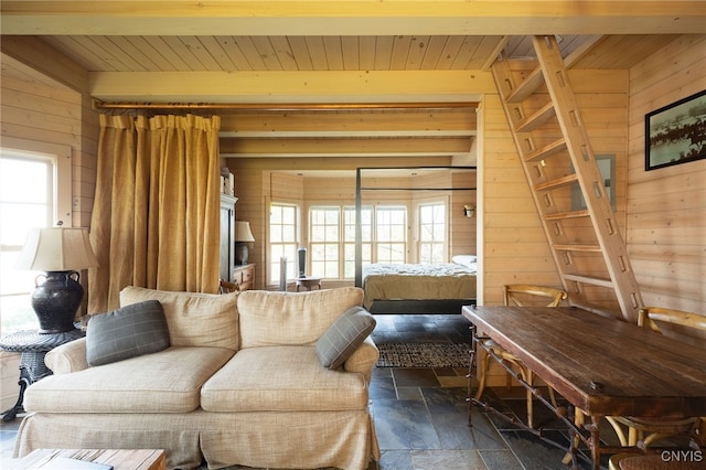 living room featuring stone tile floors, wooden walls, wooden ceiling, and beam ceiling