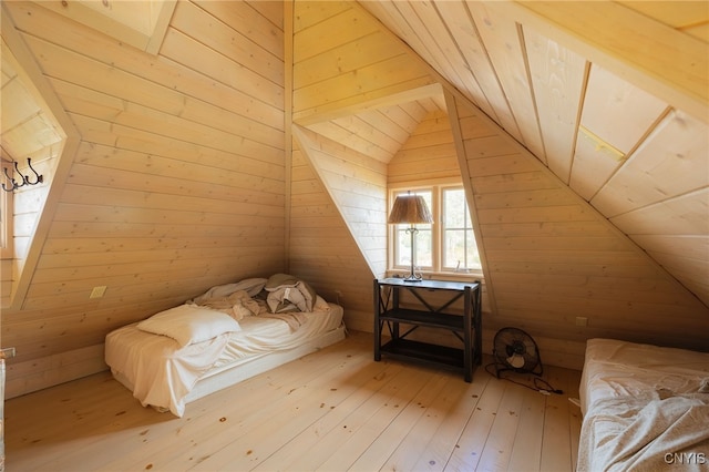 unfurnished bedroom with lofted ceiling, light wood-style floors, and wood walls