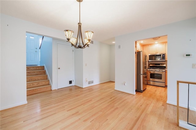 empty room featuring an inviting chandelier, stairway, light wood-style floors, and baseboards