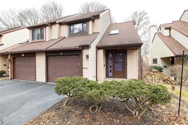 view of front of property featuring an attached garage, driveway, and roof with shingles