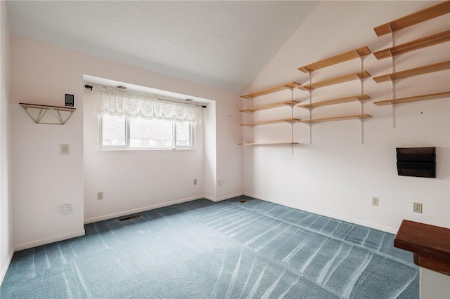 carpeted empty room with baseboards, lofted ceiling, and a textured ceiling