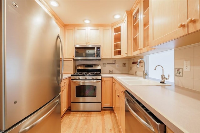 kitchen with a sink, backsplash, appliances with stainless steel finishes, and light countertops