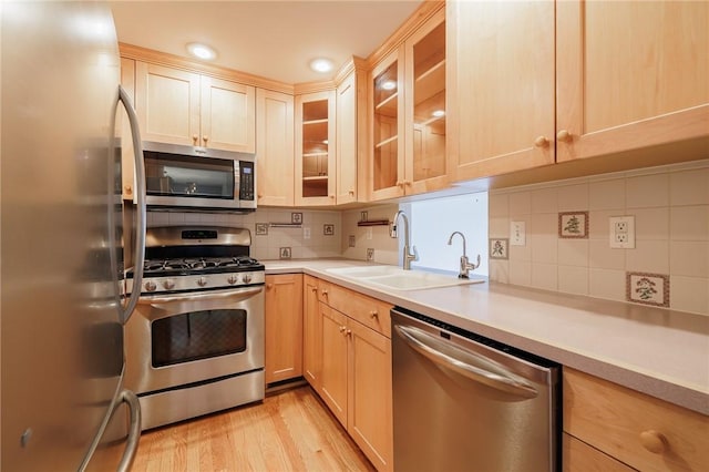 kitchen with light brown cabinetry, a sink, stainless steel appliances, light wood-style floors, and light countertops