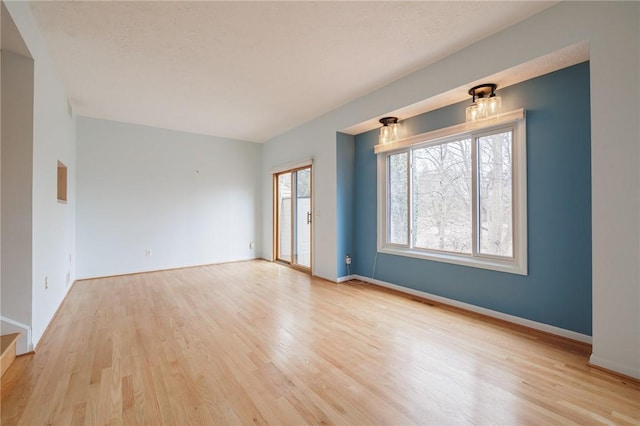 unfurnished room featuring baseboards and light wood-style floors