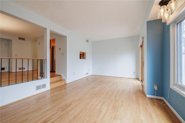 unfurnished room featuring light wood finished floors, visible vents, and a wealth of natural light