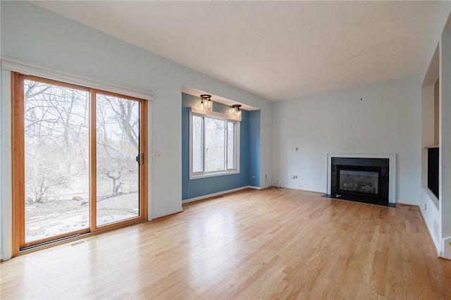 unfurnished living room featuring a fireplace with flush hearth, baseboards, visible vents, and light wood finished floors