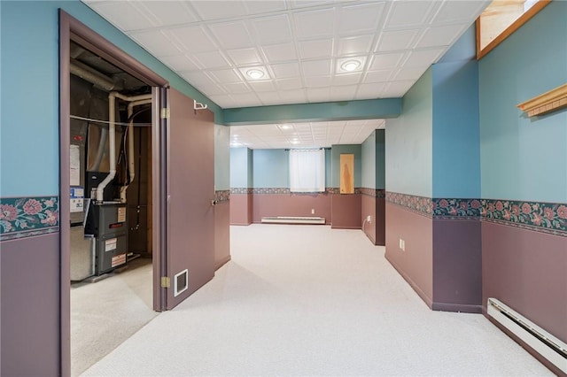 corridor with carpet flooring, a baseboard heating unit, and visible vents