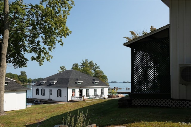 rear view of property with ac unit, a yard, and a water view