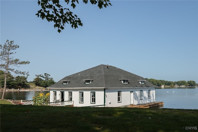 rear view of property with a water view, a lawn, and roof with shingles