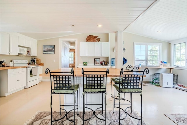 kitchen with white appliances, lofted ceiling, a breakfast bar, and butcher block counters