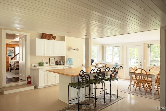 kitchen with a breakfast bar area, a healthy amount of sunlight, white cabinets, and butcher block countertops