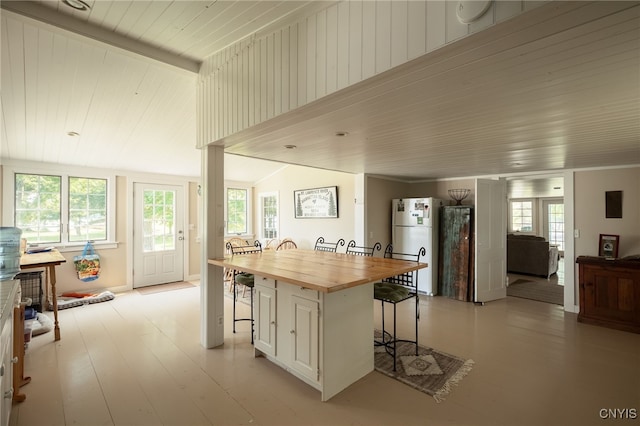 kitchen featuring a wealth of natural light, wood counters, a kitchen bar, and freestanding refrigerator