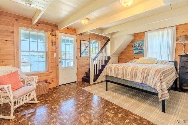 bedroom featuring beam ceiling and wooden walls