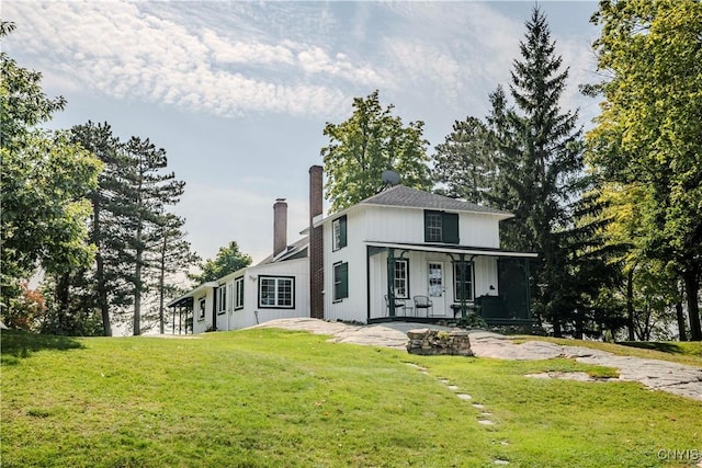 exterior space with a chimney, covered porch, and a front yard