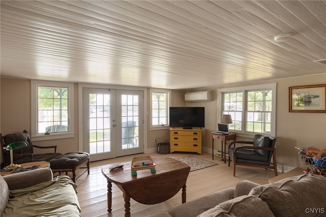 living area featuring wood finished floors, a healthy amount of sunlight, french doors, and a wall mounted AC