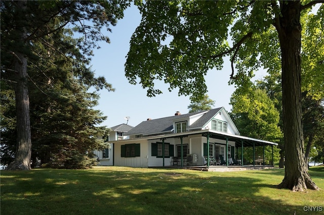 back of property featuring a yard, a chimney, and a sunroom