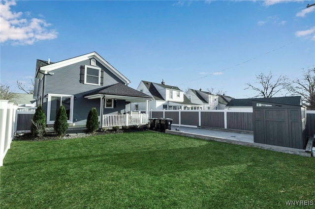 rear view of house featuring a fenced backyard, a yard, a storage shed, and an outdoor structure