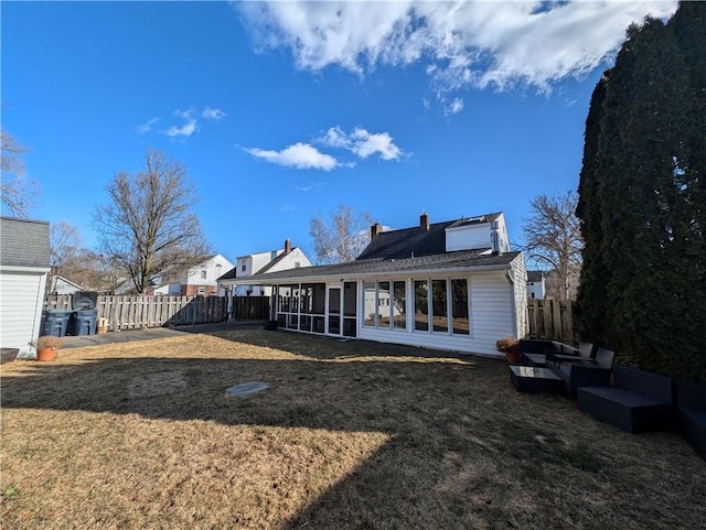 rear view of property featuring a lawn, a chimney, fence, and a sunroom