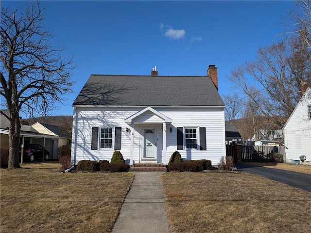 view of front facade with a chimney, a front yard, and fence