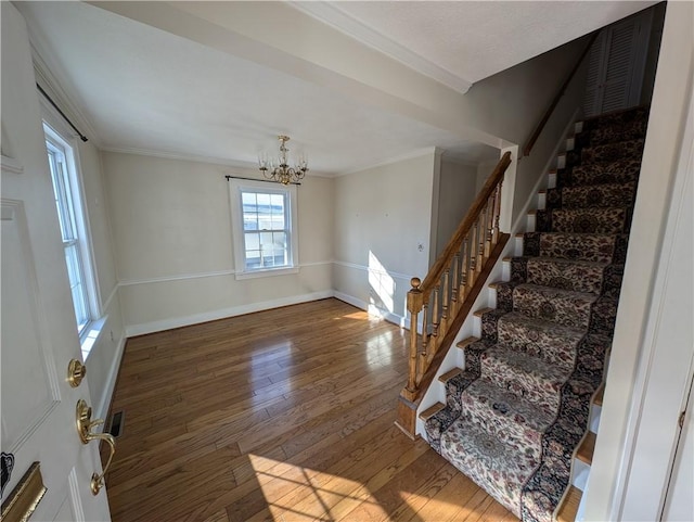 entrance foyer with crown molding, baseboards, a chandelier, stairway, and hardwood / wood-style floors